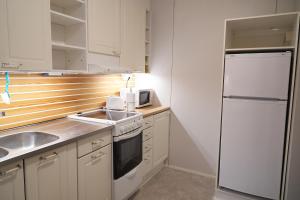 a kitchen with a white refrigerator and a sink at Rantasaunallinen yksiö in Virrat