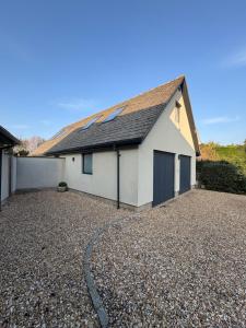 a white house with a roof on a gravel driveway at The Loft in Eynsham