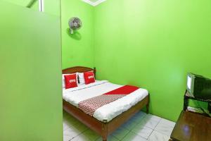 sypialnia z zielonymi ścianami i łóżkiem z czerwonymi poduszkami w obiekcie SPOT ON 91357 Hotel Mulyo w mieście Purwokerto