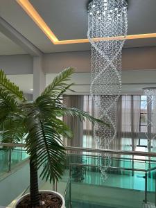 un grand lustre dans un hall avec un palmier dans l'établissement Barra Gold Hotel, à Barra Do Rio Grande