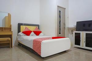 a bedroom with a bed with red pillows and a tv at Hotel O Pondok Feby Makassar in Makassar
