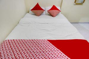 a bed with red and white sheets and pillows at Hotel O Ringin Pitu 1 Syariah in Jodoh