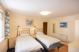 zwei Betten in einem Zimmer mit Fenster in der Unterkunft Mermaid - Pet Friendly Self Catering Holiday Cottage Hayle in Hayle