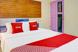 a bedroom with a bed with red and white pillows at OYO Life 91452 Ngajeng Peken Homestay in Batu