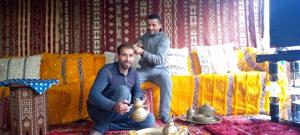 Zwei Männer sitzen auf einem Sofa und schneiden einem anderen Mann die Haare. in der Unterkunft Hôtel flora in Beni Mellal