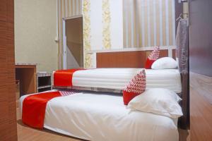 two beds in a hotel room with red and white pillows at Hotel O Sari Jeneponto in Jeneponto +17 photos