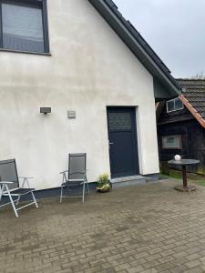due sedie sedute fuori da una casa con una porta di Ferienwohnung Hinrichshagen a Woldegk