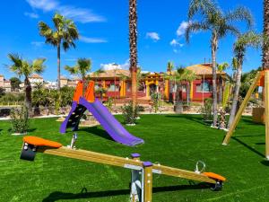 a playground in front of a house with palm trees at ON Family Playa de Doñana in Matalascañas