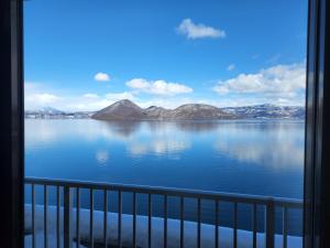 een balkon met uitzicht op een grote hoeveelheid water bij Toya-onsen Hotel Hanabi in Lake Toya