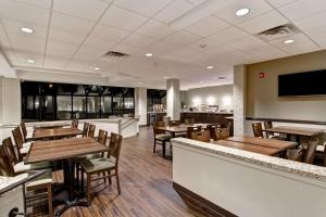 un restaurant avec des tables et des chaises en bois ainsi qu'un bar dans l'établissement Best Western London Airport Inn & Suites, à London