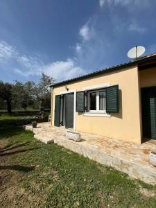 a house with green shutters and a window at Kouris Apartment Garden View in Chlomatianá