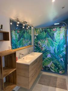 un bagno con lavandino e un grande murale di foglie di Villa 12 personnes piscine chauffée et jacuzzi a Capbreton