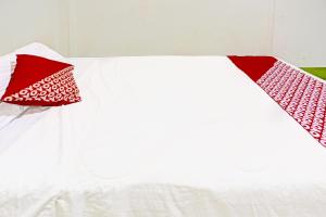 a white bed with two red pillows on it at Hotel O Suci Homestay SyariahNearKilas 7 TV in Tanjunguma