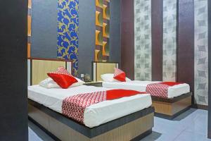 two beds with red pillows in a room at Collection O 91488 Hotel Lingkarsut Jeneponto Near Patung kuda, Jeneponto in Pannara