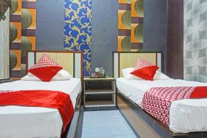 two beds with red and white pillows in a room at Collection O 91488 Hotel Lingkarsut Jeneponto Near Patung kuda, Jeneponto in Pannara +24 photos