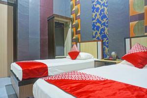 a room with two beds with red and white pillows at Collection O 91488 Hotel Lingkarsut Jeneponto Near Patung kuda, Jeneponto in Pannara