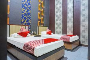 two beds in a room with red and white sheets at Collection O 91488 Hotel Lingkarsut Jeneponto Near Patung kuda, Jeneponto in Pannara