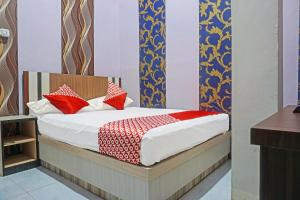 a bedroom with a bed with red pillows on it at Collection O 91488 Hotel Lingkarsut Jeneponto Near Patung kuda, Jeneponto in Pannara