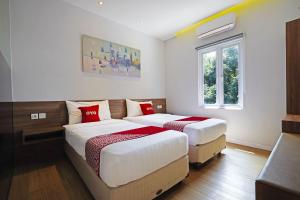 una camera da letto con due letti e una finestra di Collection O Dago Near Taman Hutan Raya Formerly Regia Dago a Bandung