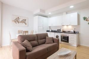 a living room with a brown couch and a kitchen at Teatro Plaza Apartments in Málaga