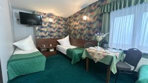 a hotel room with two beds and a table and a tv at Noclegi I Restauracja Zodiak in Gliwice