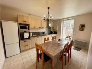 a kitchen with a table with chairs and a white refrigerator at Gîtes confortables près de Beauval avec wifi et parking - FR-1-491-457 in Meusnes