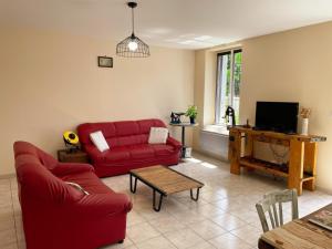 a living room with a red couch and a tv at Gîtes confortables près de Beauval avec wifi et parking - FR-1-491-457 in Meusnes