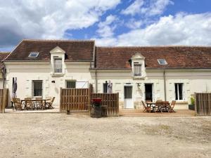 a house with tables and chairs in front of it at Gîte confortable avec Wi-Fi, proche Zoo de Beauval et châteaux de la Loire - FR-1-491-458 in Meusnes