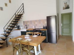 a kitchen and dining room with a table and a refrigerator at Charming comfortable barn in Coutras