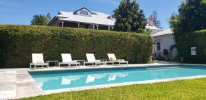 a swimming pool with lounge chairs and a house at Ballina Manor Boutique Hotel in Ballina
