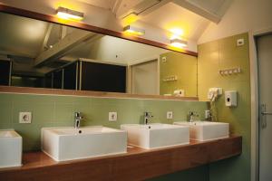 un bagno con tre lavandini e un grande specchio di King Kong Hostel a Rotterdam