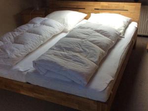 a bed with white sheets and pillows on it at Thölkes Haus am Meer in Butjadingen