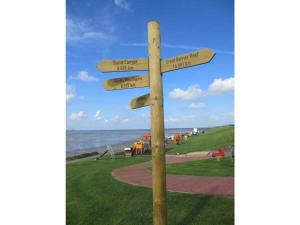 a wooden sign with four arrows on a pole at Thölkes Haus am Meer in Butjadingen