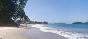 a beach with people walking on the sand and water at Casa da Aninha na Prainha - Valor para 4 pessoas in Paraty