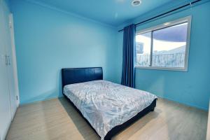 a blue bedroom with a bed and a window at Warm and romantic cottage-4Bed-9guests in Tarneit