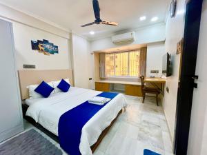 Un dormitorio con una cama con almohadas azules y un escritorio. en UrbanNest Service Apartments Powai, en Bombay