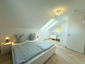 a white bedroom with a bed with blue sheets at Wangermeer Perle II in Wangerland