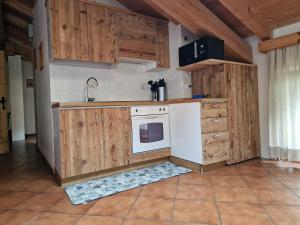a kitchen with wooden cabinets and a white appliance at Casa Campetta in Comano Terme