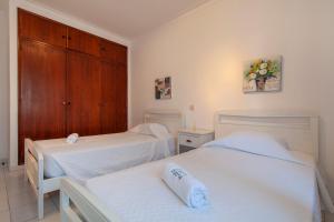 two beds in a room with white walls and wooden cabinets at Rio a Vista Praia da Rocha Flat in Portimão