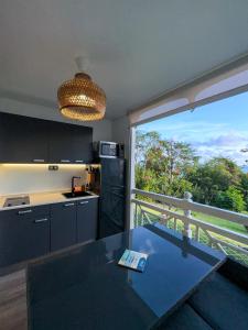 a kitchen with a table and a large window at Studio vue mer avec piscine - Le Diamant in Le Diamant