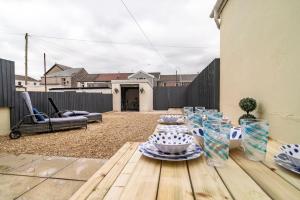 eine Terrasse mit einem Holztisch mit Geschirr darauf in der Unterkunft Ty Gwyrdd, 3 bedroom house, sleeps 7, Near Bike Park Wales in Abercanaid