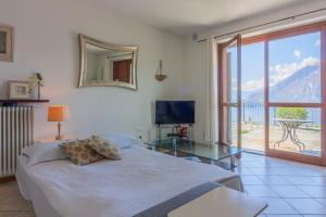 1 dormitorio con 1 cama, mesa de cristal y TV en Golden View Apartment, en Perledo