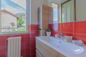 a bathroom with a sink and a window and red tiles at Candy House in Varenna +46 photos