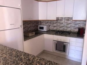 a kitchen with white cabinets and a white microwave at Paraíso in Cumbre del Sol
