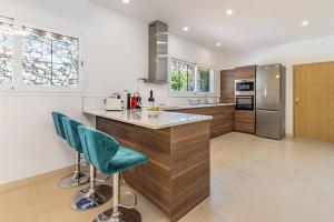 a kitchen with a counter and two blue bar stools at Luxury villa with tennis & pool in Málaga +51 photos