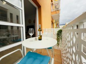 a white table with wine glasses and blue chairs on a balcony at Mansa Beach I - Vv Playa San Juan in Guía de Isora