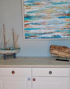 a painting of a boat sitting on top of a dresser at Aquamarine - Gemstone Getaway in Vale do Lobo