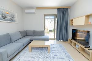un salon avec un canapé bleu et une télévision dans l'établissement Pool View Apartment - Diamond Hill Resort & SPA, à Vlorë