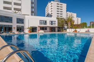 a large pool with blue water in front of a building at Cozy Apartment with indoor pool in Albufeira