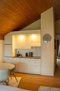 a kitchen with white cabinets and a wooden ceiling at Surfers Lodge with Beach, near Interlaken in Därligen